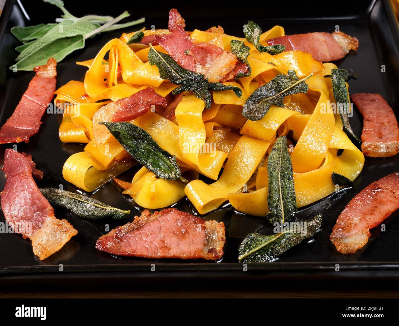 Pappardelle (Nudeln etwas breiter als Tagliatelle) ist ein typisches italienisches Nudelgericht. Einfach zuzubereiten und sehr lecker. Roher Schinken, Salbei und Olivenöl. Stockfoto