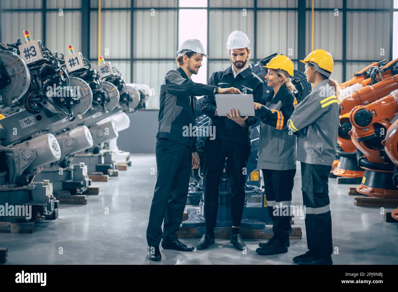 Die Gruppe der Ingenieure steht im Gespräch. Teamarbeit in der Branche – Mitarbeitergespräch. Zusammenkunft des Montagewerks für Roboterarme mit Laptop CO Stockfoto