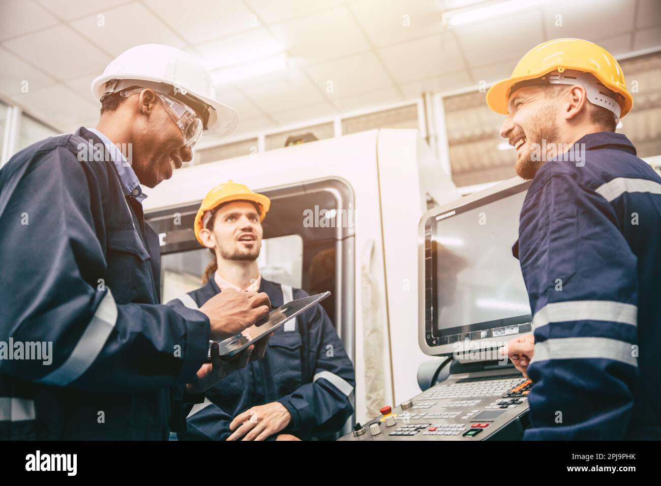 Eine Gruppe männlicher Diversity Engineer-Mitarbeiter genießt es, sich zu entspannen, fröhliche Scherze zu erzählen, lustig zu reden und lachen Freund am Fabrikarbeitsplatz Stockfoto
