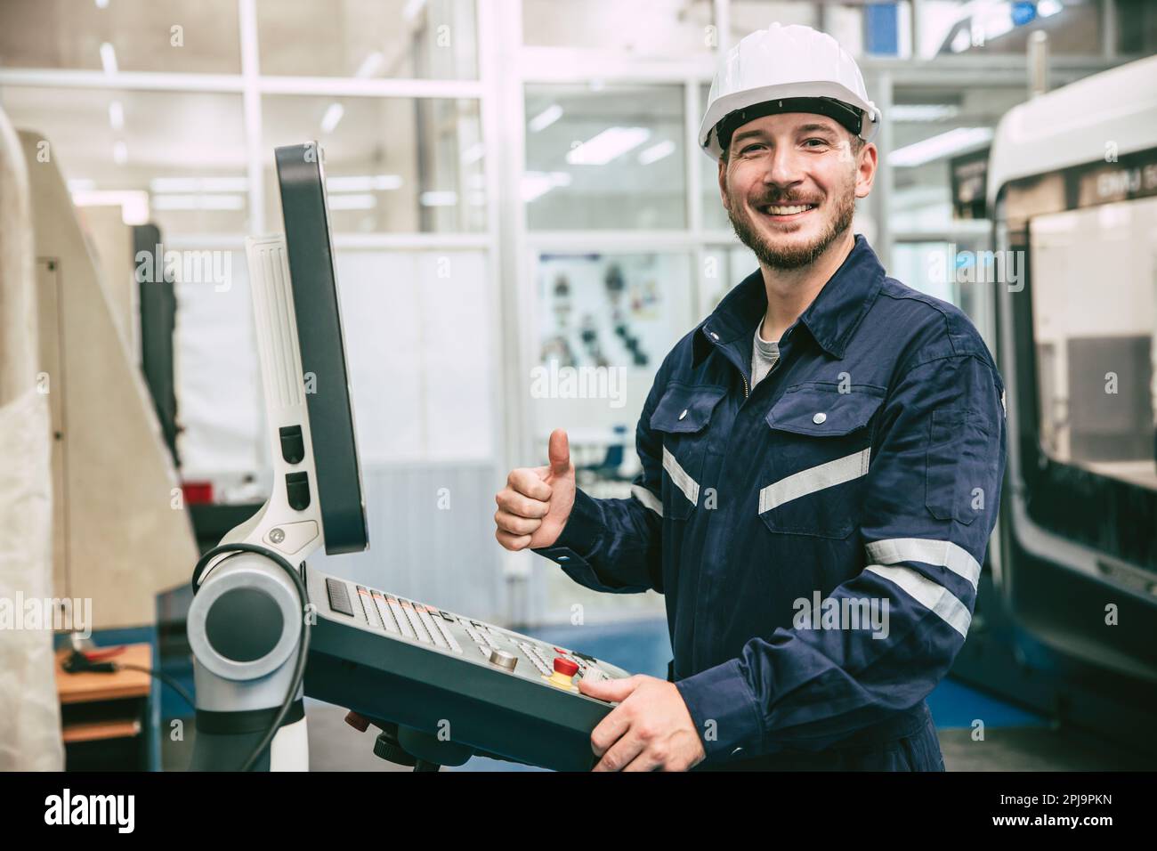 Ein glückliches Lächeln zeigt den Daumen nach oben Ingenieur arbeitet mit CNC Lathe Machine in einer modernen Metallfabrik Stockfoto