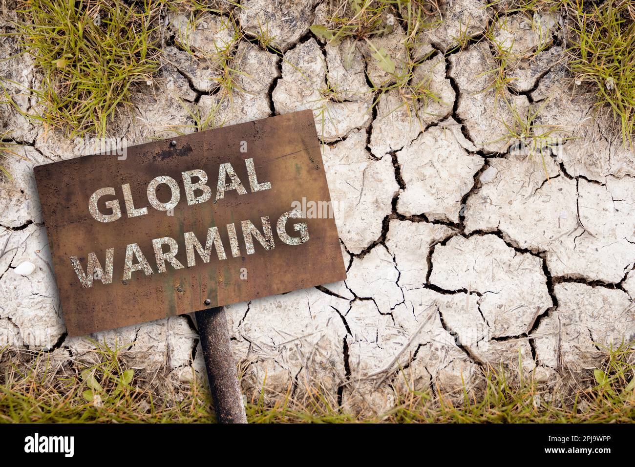 Rostiges Schild mit Text GLOBALE ERWÄRMUNG auf einem Hintergrund von trockenem, gerissenem Boden. Das Konzept des Klimawandels. Hochwertiges Foto Stockfoto