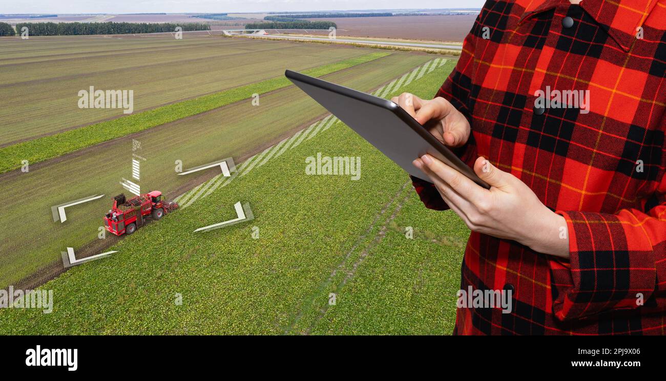 Der Landwirt verwendet ein digitales Tablet zur Steuerung der autonomen Erntemaschine. Konzept der intelligenten Landwirtschaft. Hochwertiges Foto Stockfoto