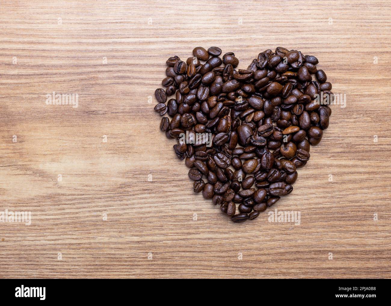 Konzept von Liebe oder Kaffee lieben. Herzform aus Kaffeebohnen auf einem Holzbrett. Stockfoto