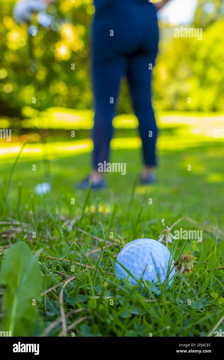 Golfball auf dem rauen Gras und Golfer mit auf der Suche nach