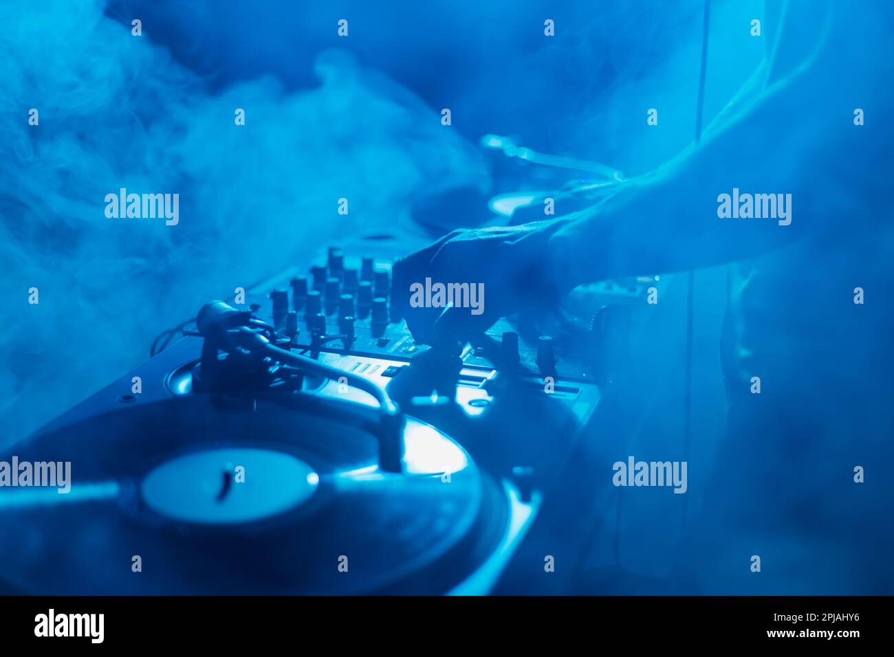 Silhouette eines Club-DJs, der Musik in Rauch auf der Bühne mischt. Professionelle Disc-Witzfiguren auf Techno-Party Stockfoto