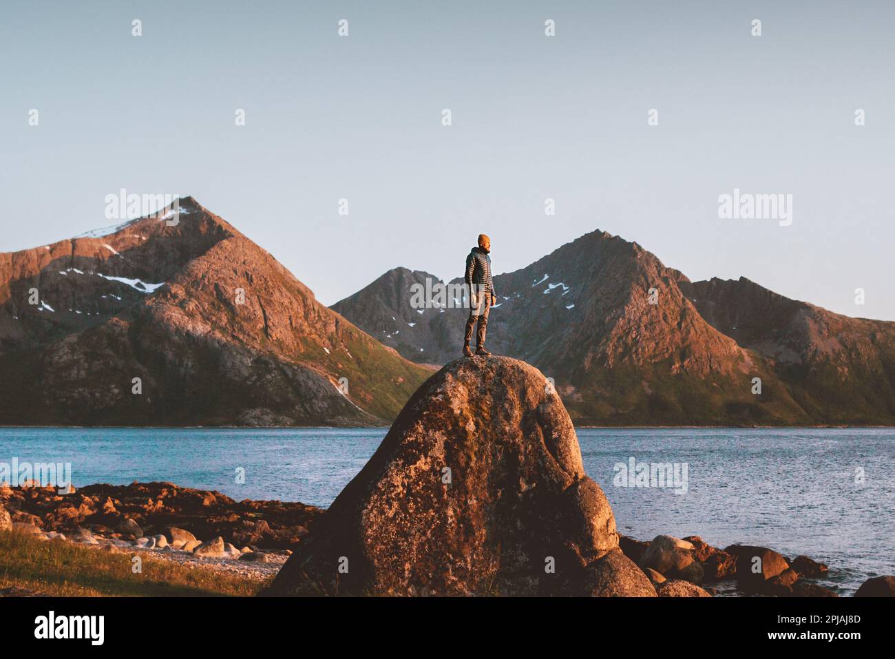 Ein Mann, der in Norwegen unterwegs ist Outdoor-Abenteuer Lifestyle Sunset Mountains Landschaft Touristen Stand alone on Rock Freedom Concept Stockfoto