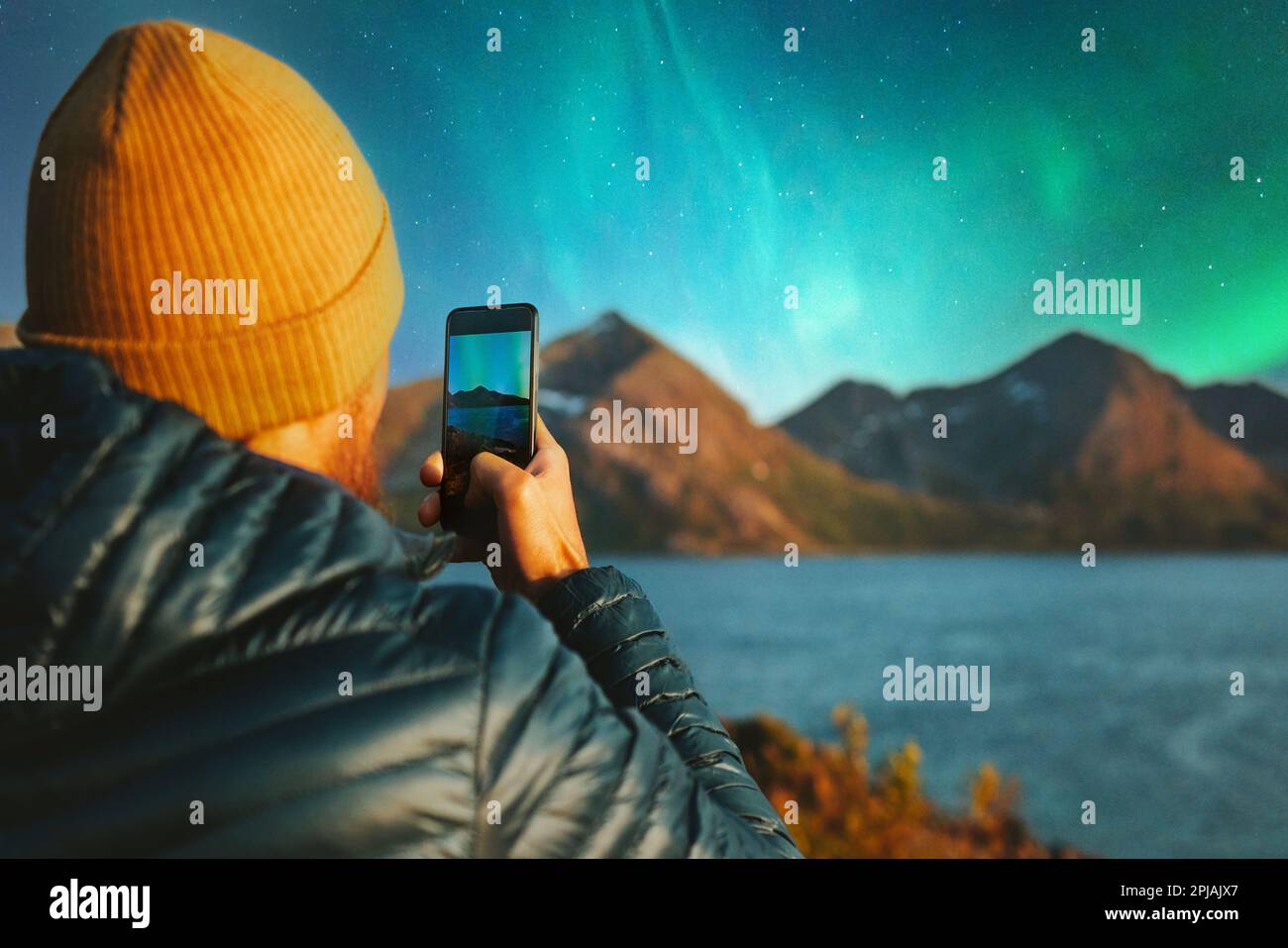 Mann mit Smartphone fotografiert Nordlichter Winterreisen in Norwegen Abenteuer Urlaub Outdoor Blogger Beeinflusser Lifestyle modern online tec Stockfoto