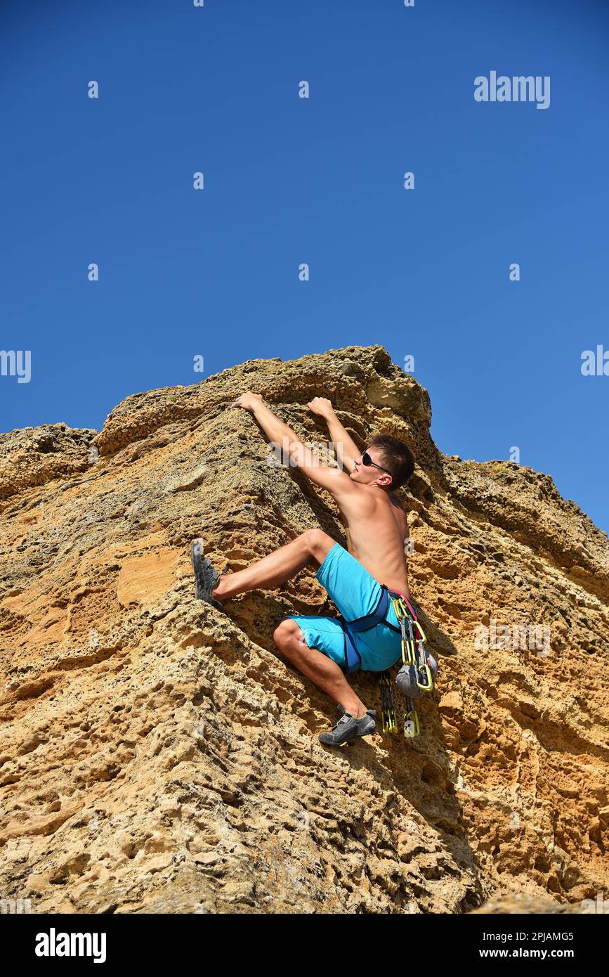 Ein sportlicher Felskletterer klettert auf eine Felswand Stockfoto