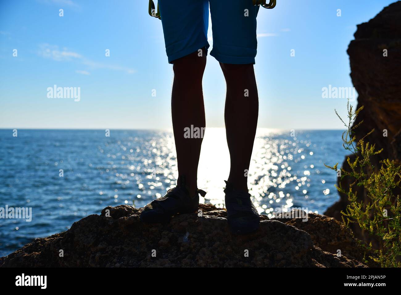 Fußkletterer auf einer Klippe, Sonnenschein im Meer im Hintergrund Stockfoto