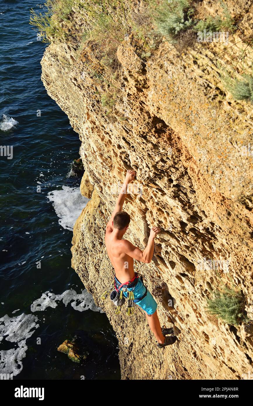 Männlicher Kletterer klettert auf eine Felswand Stockfoto