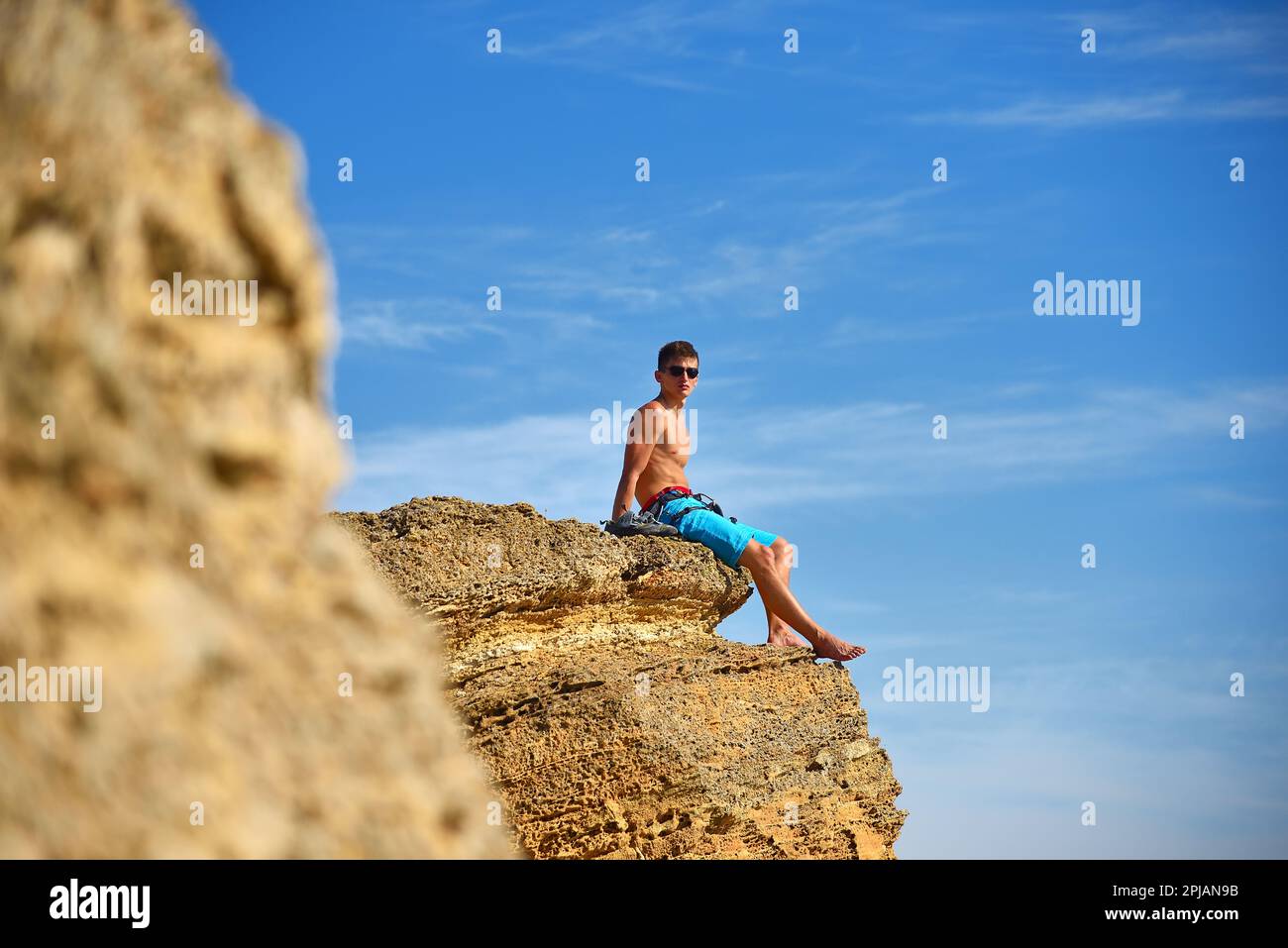 Männlicher Kletterer, der nach dem Klettern auf gelbem Felsen ruht Stockfoto