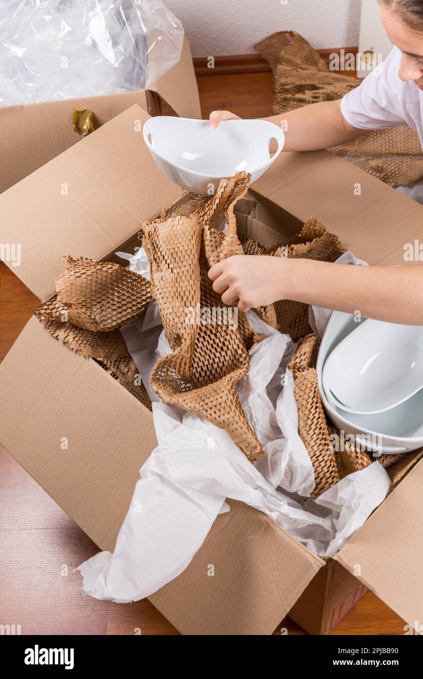 Detail einer Frau, die zerbrechliche Artikel mit zerknittertem Packpapier verpackt. Konzept des ein- und Auszugs Stockfoto