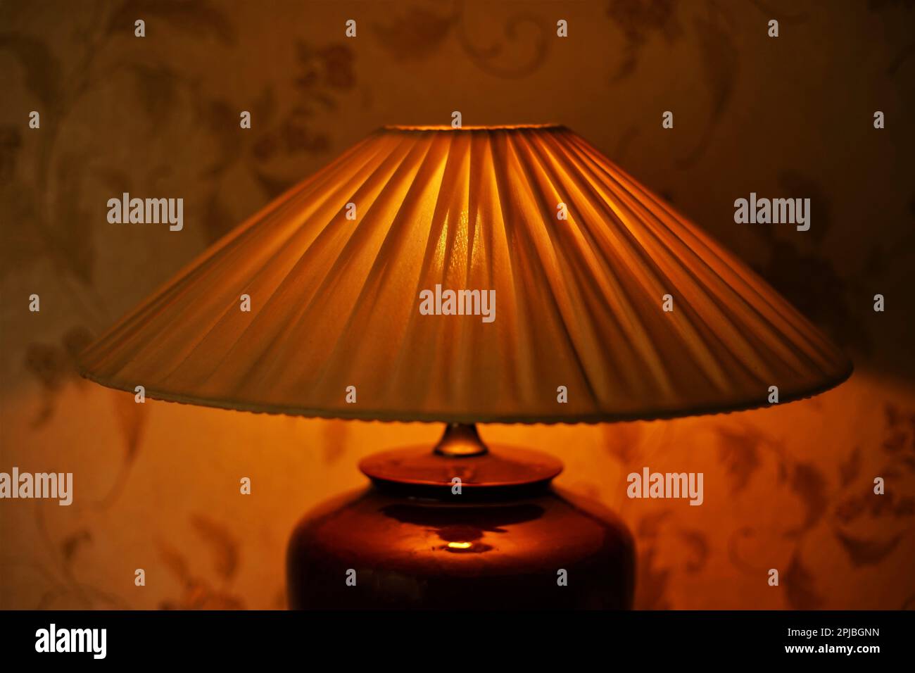 Faltenlampenschirm mit warmem Licht im dunklen Raum, Nahaufnahme Stockfoto