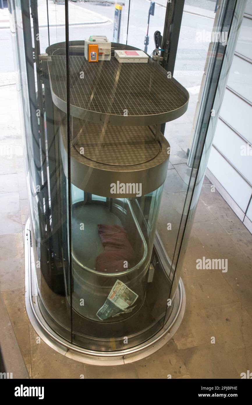 Obdachloser, der in einem Glasaufzug im Zentrum von London schläft Stockfoto