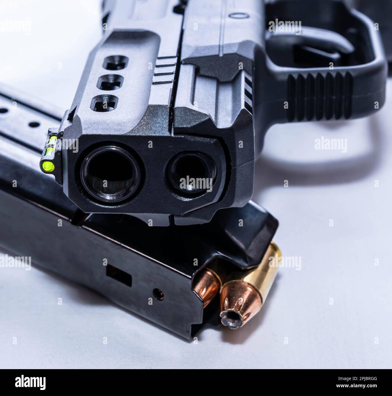 Eine schwarze Pistole, 380acp in einer Kammer, mit einem beladenen Magazin darunter auf weißem Hintergrund Stockfoto