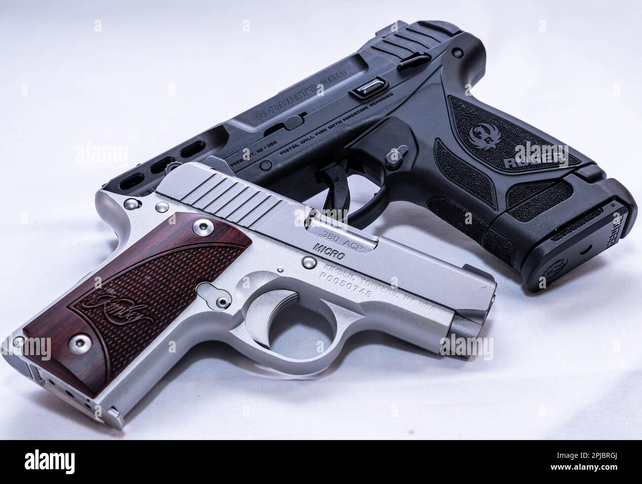 Eine Kimber 380 Micro 1911-Pistole aus Edelstahl mit Holzgriffen und eine schwarze Ruger Security 380 Stockfoto Eine Kimber 380 Micro 1911-Pistole aus Edelstahl mit Holzgriffen und eine schwarze Ruger Security 380 Stockfoto