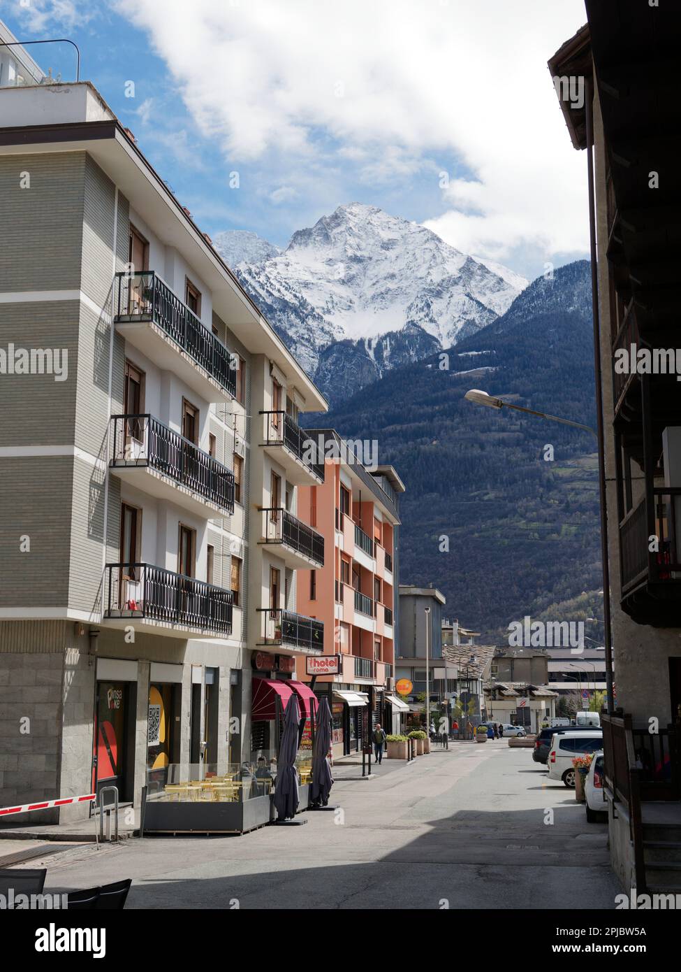 Apartmentblöcke in einer Straße in Aosta mit schneebedeckten Bergen in den alpen. Aosta-Tal, Italien Stockfoto