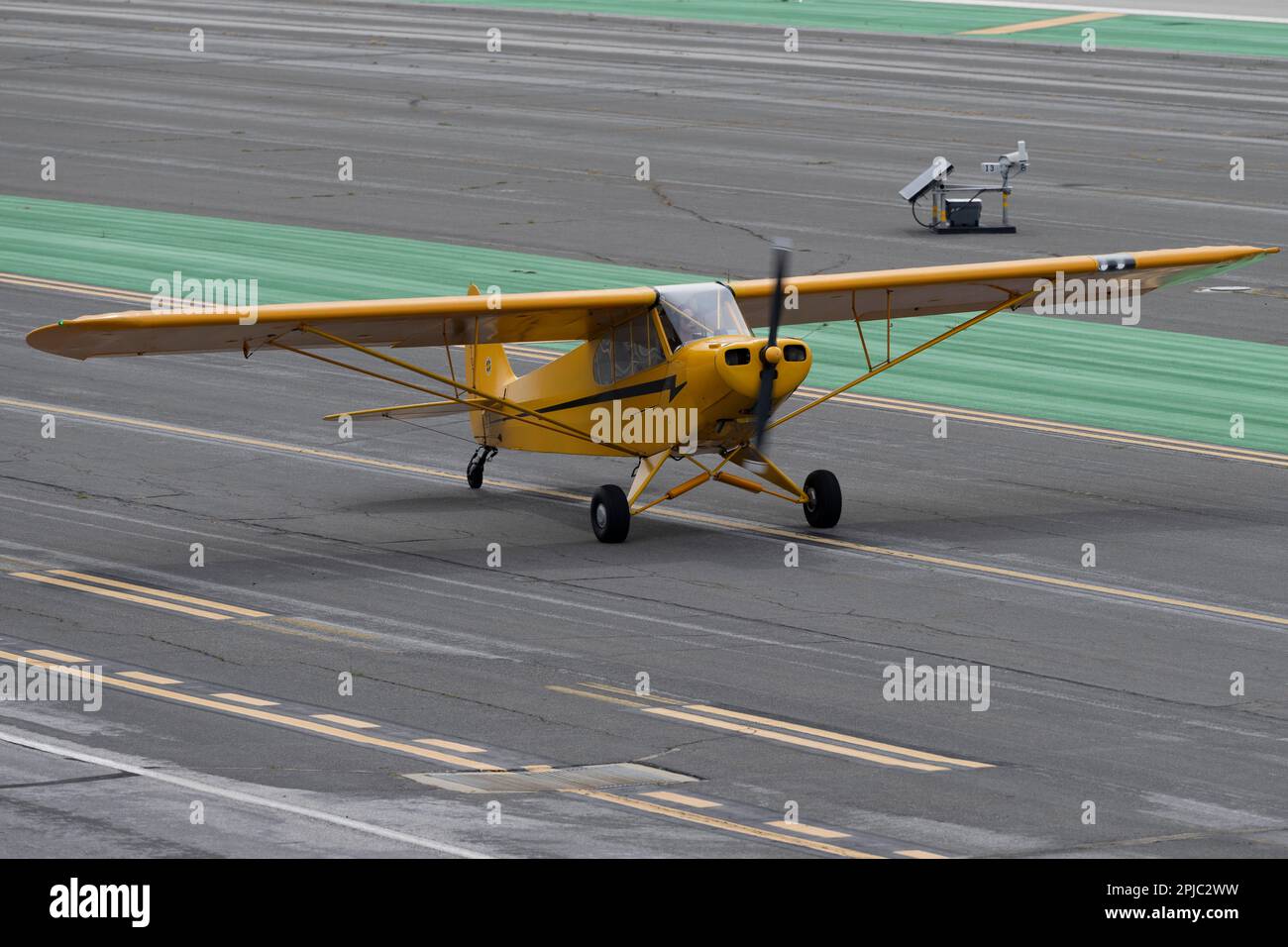 Santa Monica, Kalifornien, USA. 31. März 2023. Ein Pilot in einem alten J3 Piper Cub Waves, bevor er auf der Runway 21 des Flughafens Santa Monica abhebt. Santa Monica Airport (ICAO: KSMO) ist ein Flughafen für allgemeine Luftfahrt, der FBOs, Flugschulen und Hobbybastler anbietet. Seine Lage in der Nähe von Wohngebieten und seine kurze Start- und Landebahn haben zu Kontroversen geführt und zu Bemühungen geführt, den Flughafen zu schließen. Die FAA kündigte an, dass der Flughafen 2028 geschlossen und in einen öffentlichen Park umgewandelt wird. Der Flughafen hat eine reiche Geschichte und wird seit 1917 für Flugzwecke genutzt, wo er die Heimat des Douglas Aircraft Corpor war Stockfoto