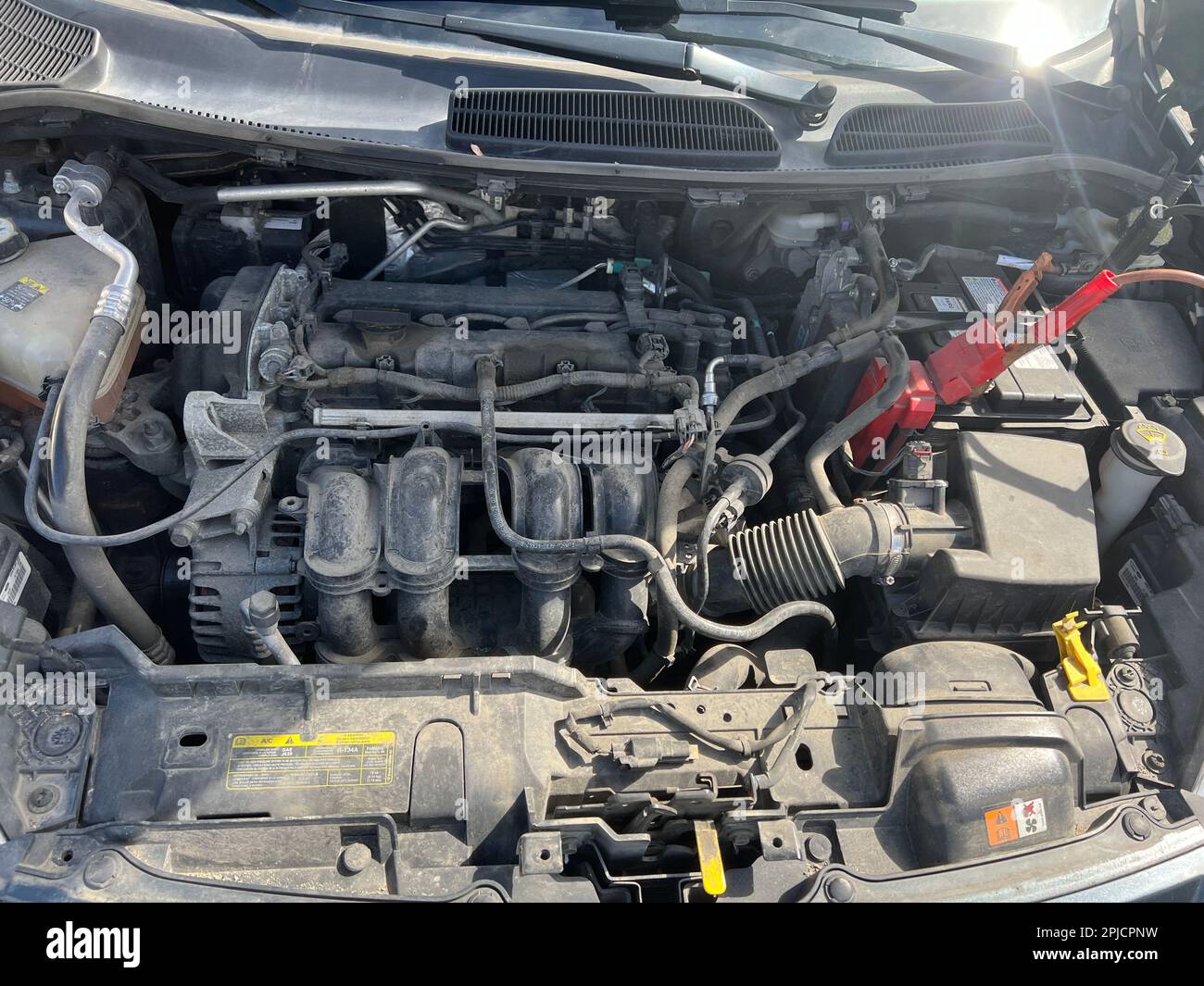 Aufladen einer Autobatterie im Winter. Hilfe auf der Straße. Nahaufnahme. Hochspannungsleitungen an die Fahrzeugbatterie anschließen. Reanimation des Autos bei schweren Winterbedingungen Stockfoto