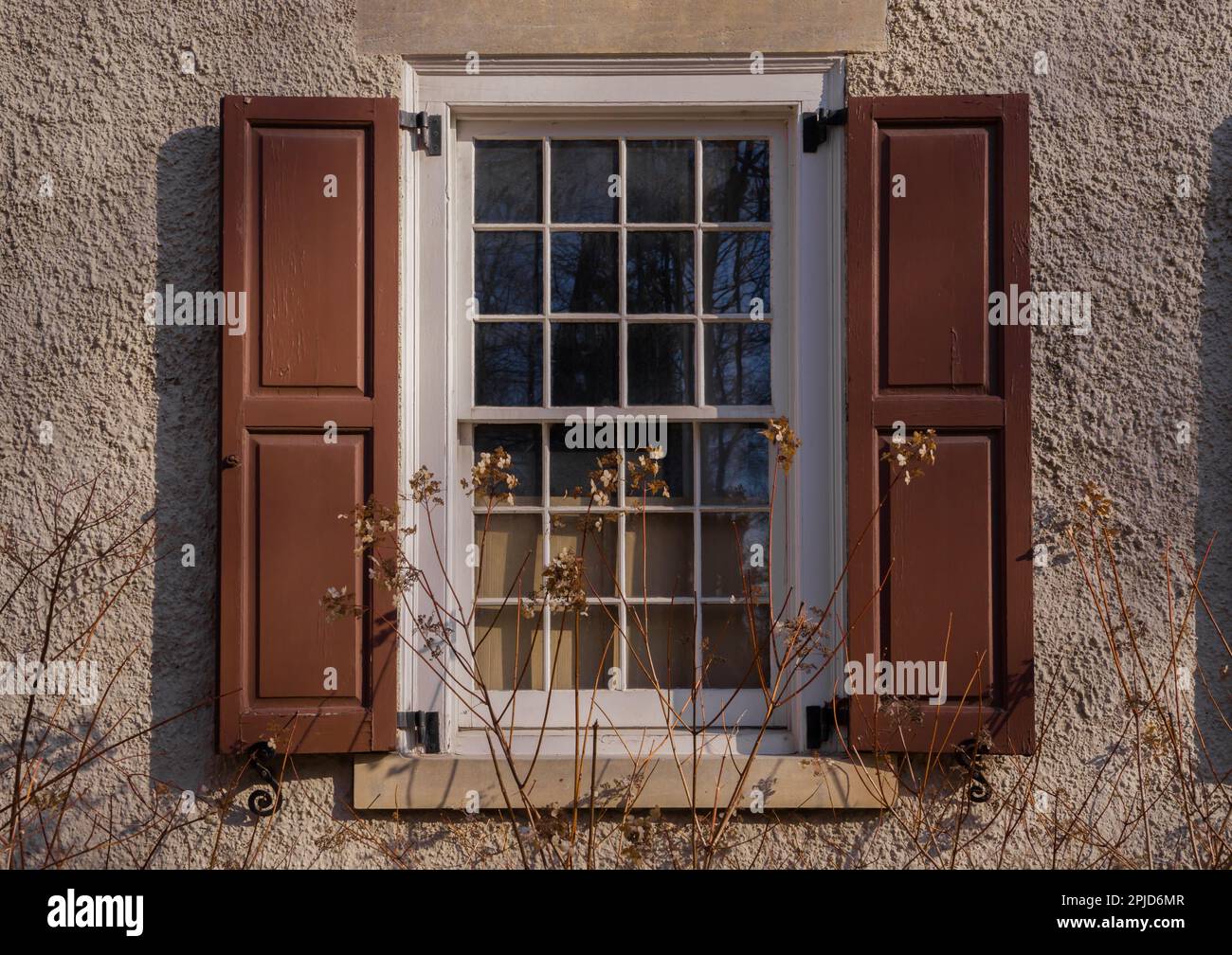 Fenster mit Holzläden und Blumen vor einer Steinmauer. Architekturdetails Stockfoto