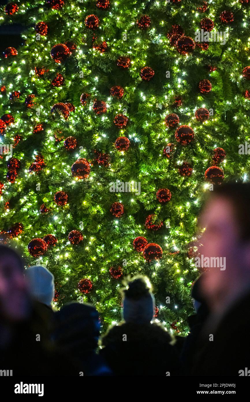 Leute stehen vor einem großen dekorierten weihnachtsbaum Stockfoto