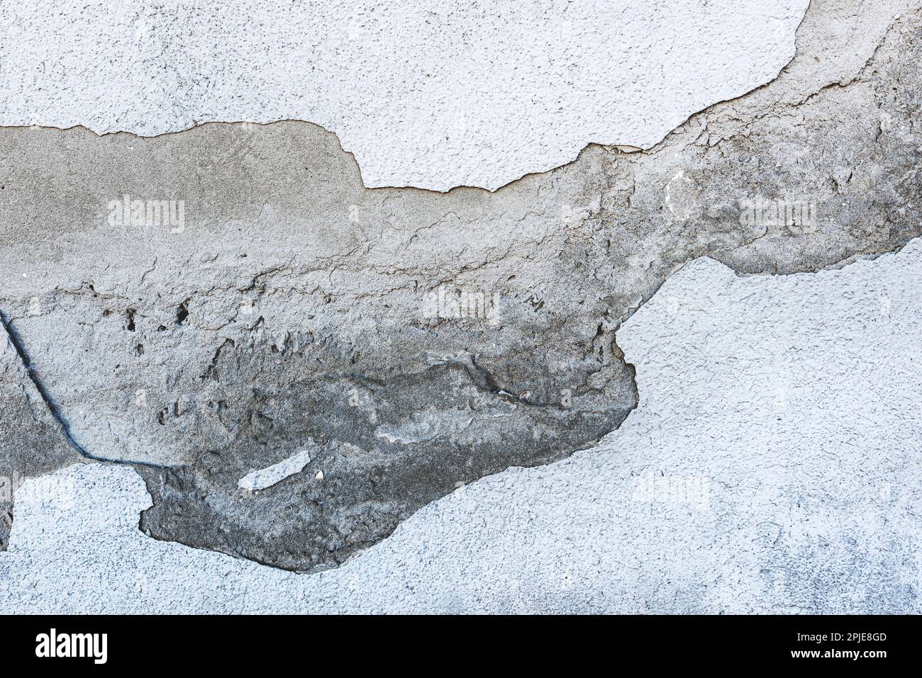 Beschädigte Stuckwand mit gerissener Oberfläche als Hintergrund Stockfoto