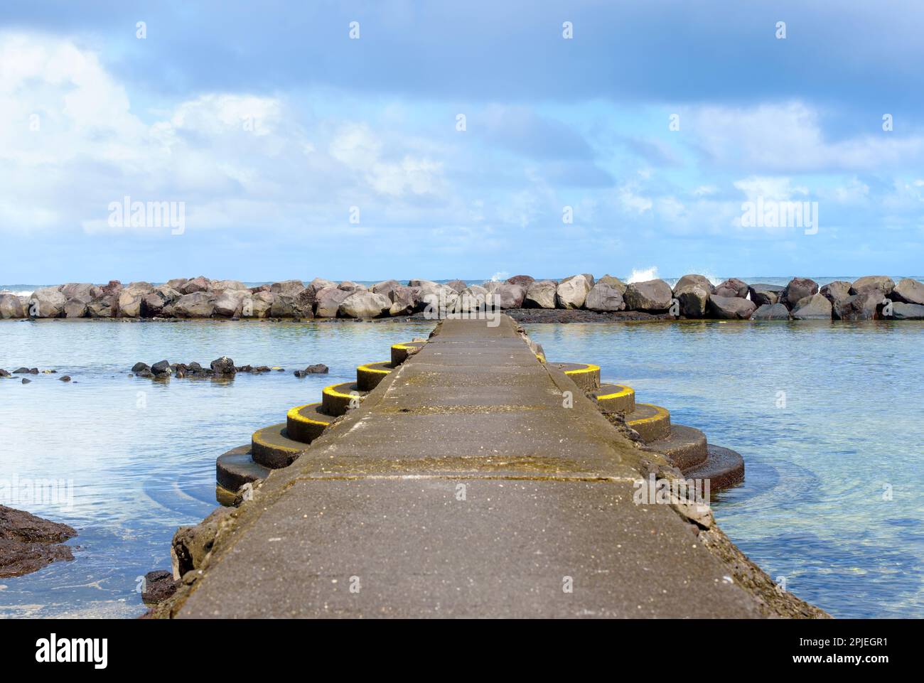 Die Schönheit eines Strands auf Hawaii mit einem ausgewiesenen Schwimmbereich mit einem Steinpier und Stufen, die durch eine riesige Mauer aus Steinen vom Ozean getrennt sind. Stockfoto