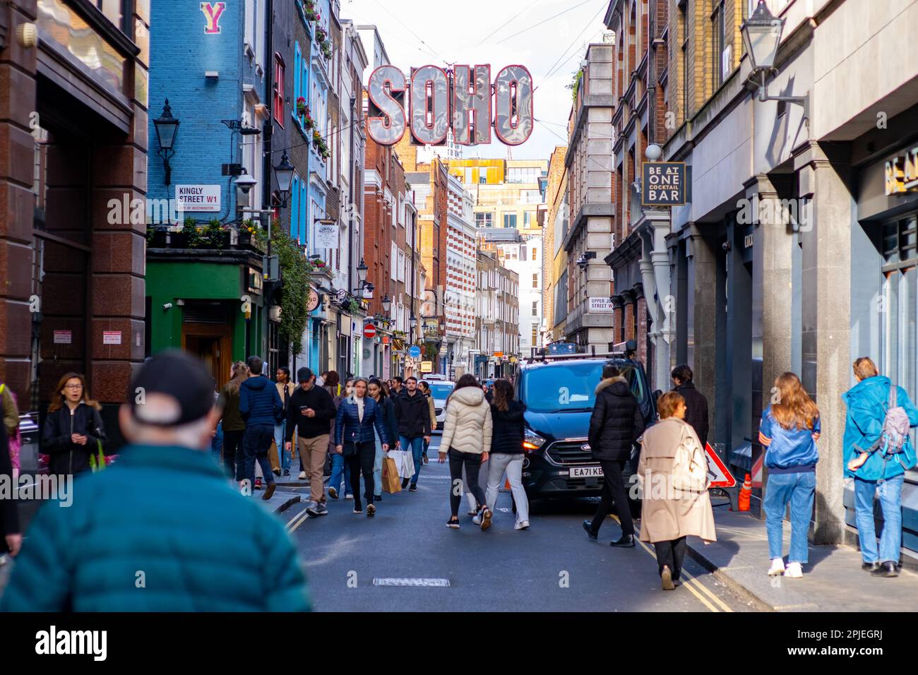 Shoppers on Beak Street in Soho, Central London, an einem geschäftigen Samstagnachmittag, 2023. April. Das große „Soho“-Schild befindet sich über der Straße. Stockfoto