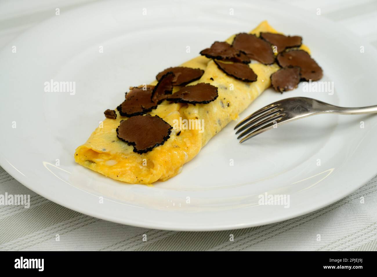 Französische Trüffel-Omelette-Eier oder Omelette-Auc-Trüffel mit schwarzen Sommertrüffeln auf einem weißen Teller Stockfoto