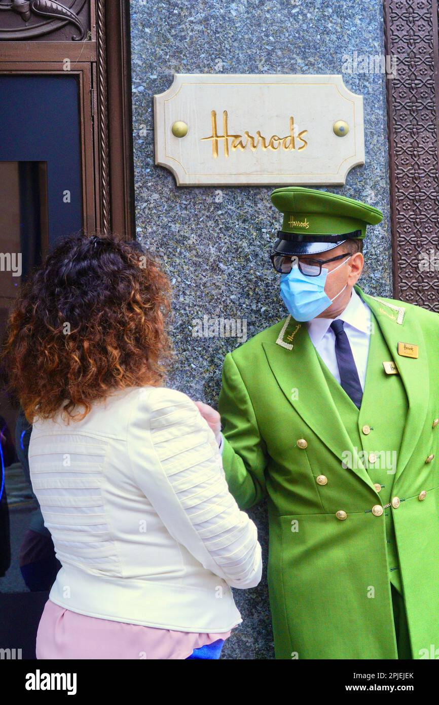 London, England, 20. August 2021: Berühmter Portier von Harrod mit Gesichtsmaske und unverwechselbarer leuchtend grüner, goldgeknöpfter Uniform. Stockfoto