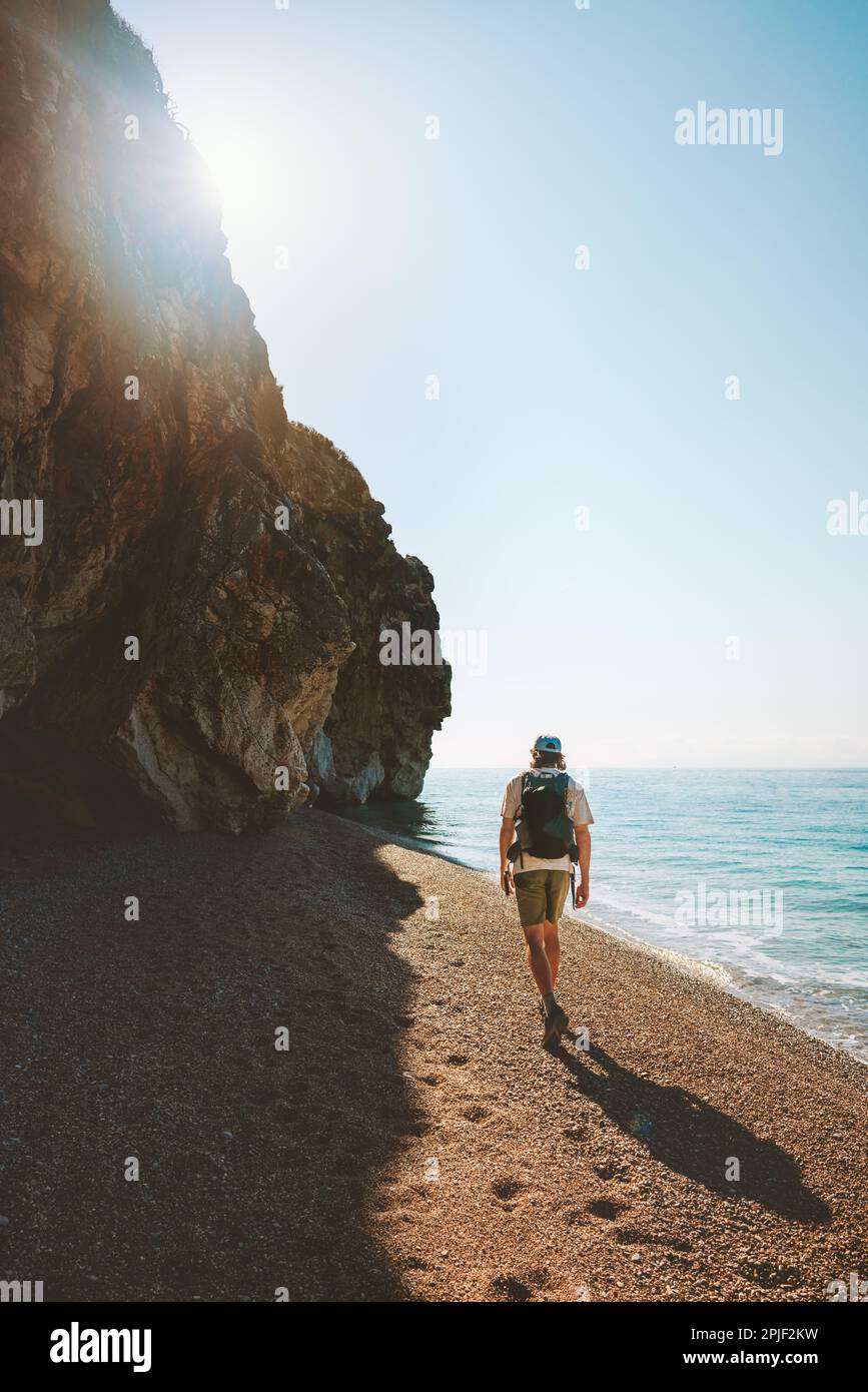 Ein Tourist mit Rucksack, der am leeren Strand spaziert und alleine im Freien Urlaub macht Stockfoto