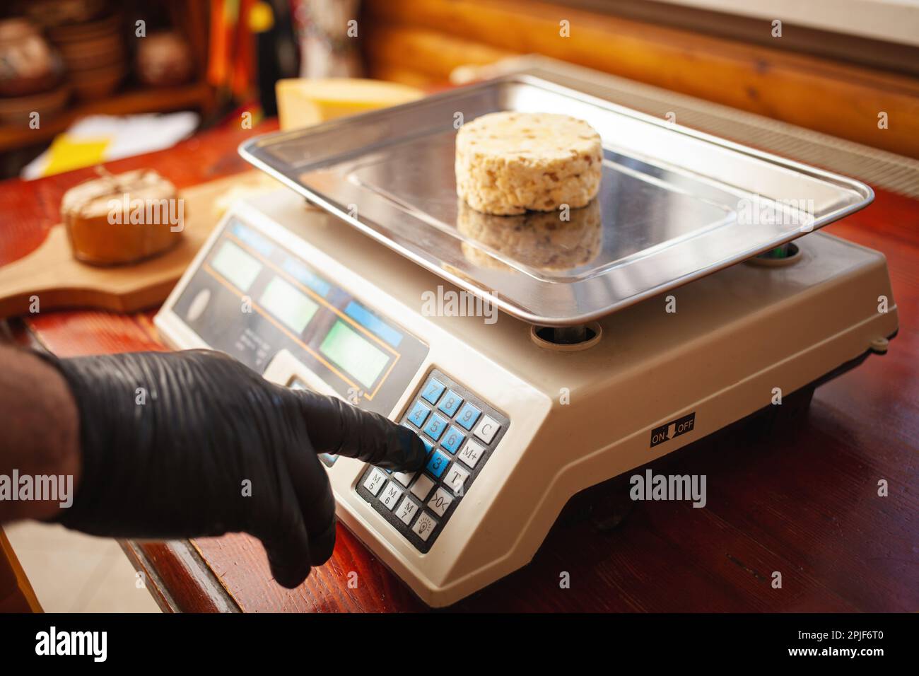 Der Käsehersteller wiegt Käse auf Waage, Heimproduktion, Geschäft. Stockfoto