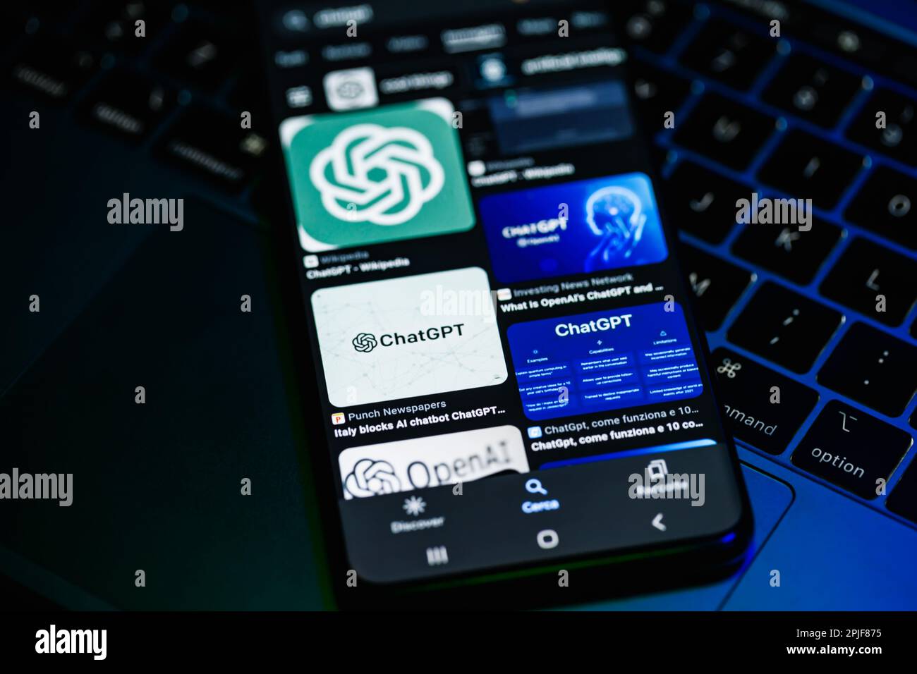 ITALIEN - 31. März 2023: Smartphone-Bildschirm mit Bildern von Chat gpt und Open Ai, mit Hintergrund und beleuchteter Tastatur eines Laptops. Italienische Blockade. Stockfoto