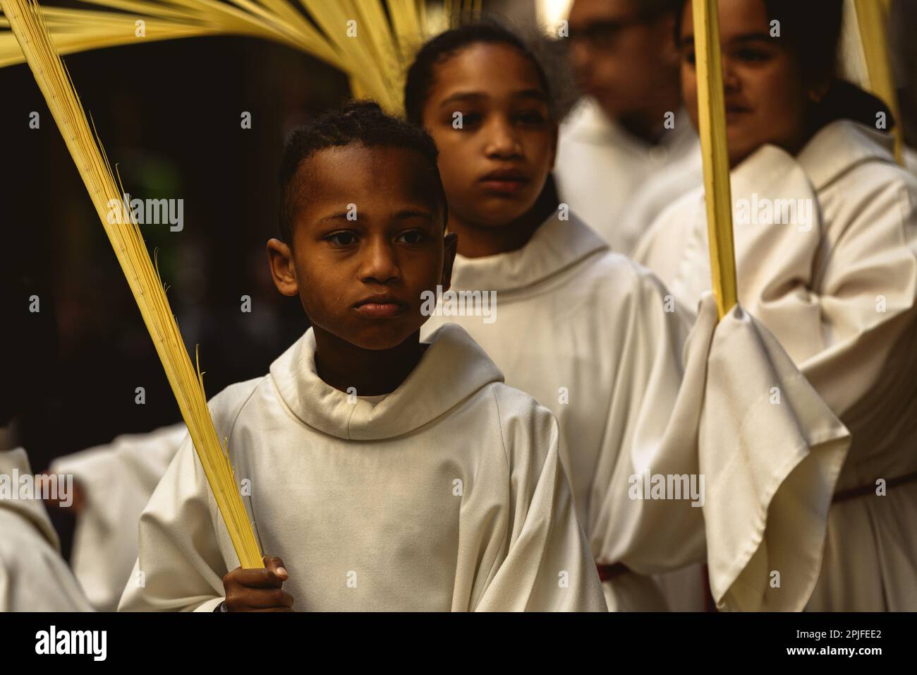 Barcelona, Spanien. 2. April 2023. Junge Bußgesellen der Brüderschaft „Gran Poder und Macarena Esperanza“ gehen die Straße entlang und halten während der Palmensonntagsprozession in Barcelona einen Palmenzweig. Kredit: Matthias Oesterle/Alamy Live News Stockfoto