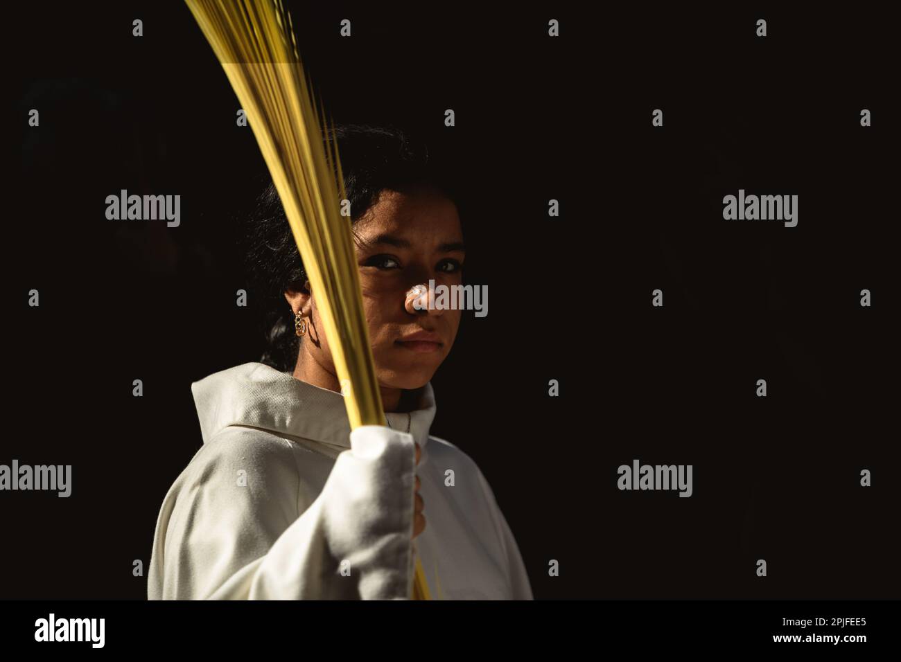 Barcelona, Spanien. 2. April 2023. Ein junger Bußgesicht der Brüderschaft „Gran Poder und Macarena Esperanza“ läuft auf der Straße mit einem Palmenzweig während der Palmensonntagsprozession in Barcelona. Kredit: Matthias Oesterle/Alamy Live News Stockfoto