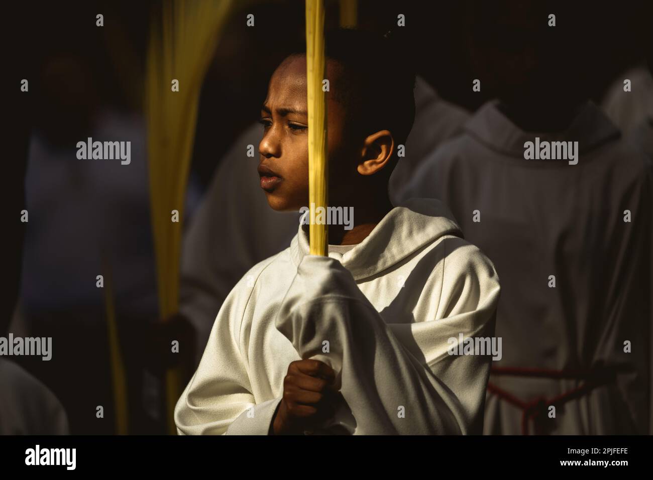 Barcelona, Spanien. 2. April 2023. Ein junger Bußgesicht der Brüderschaft „Gran Poder und Macarena Esperanza“ läuft auf der Straße mit einem Palmenzweig während der Palmensonntagsprozession in Barcelona. Kredit: Matthias Oesterle/Alamy Live News Stockfoto