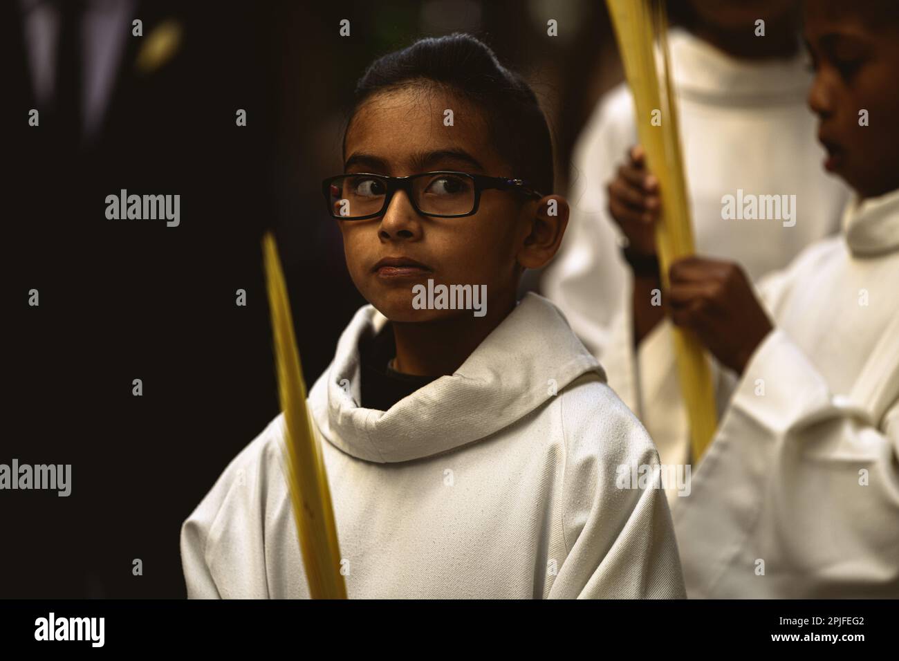 Barcelona, Spanien. 2. April 2023. Ein junger Bußgesicht der Brüderschaft „Gran Poder und Macarena Esperanza“ läuft auf der Straße mit einem Palmenzweig während der Palmensonntagsprozession in Barcelona. Kredit: Matthias Oesterle/Alamy Live News Stockfoto