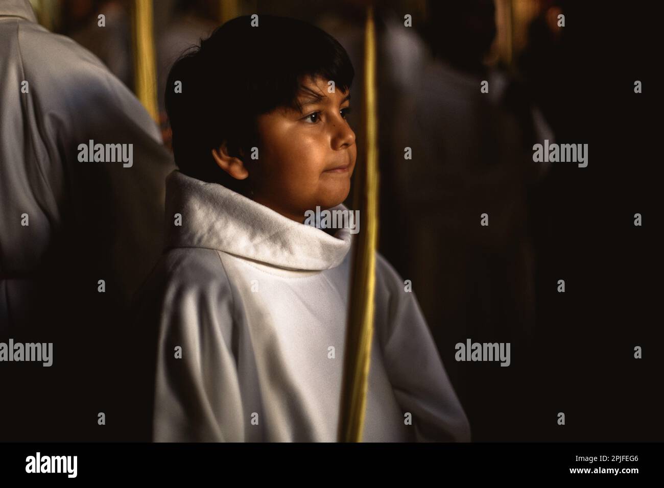 Barcelona, Spanien. 2. April 2023. Ein junger Bußgesicht der Brüderschaft „Gran Poder und Macarena Esperanza“ läuft auf der Straße mit einem Palmenzweig während der Palmensonntagsprozession in Barcelona. Kredit: Matthias Oesterle/Alamy Live News Stockfoto