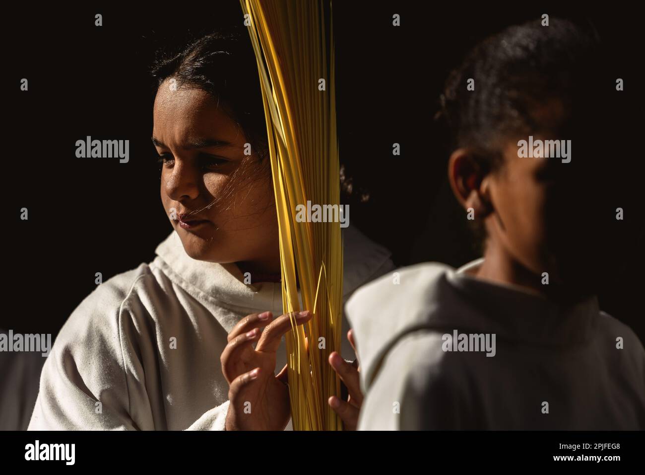 Barcelona, Spanien. 2. April 2023. Ein junger Bußgesicht der Brüderschaft „Gran Poder und Macarena Esperanza“ läuft auf der Straße mit einem Palmenzweig während der Palmensonntagsprozession in Barcelona. Kredit: Matthias Oesterle/Alamy Live News Stockfoto