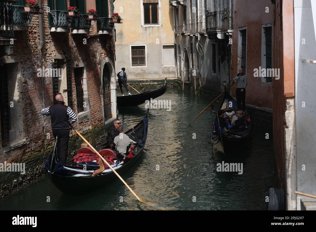 Gondoliere rudern ihre Gondeln mit Touristen an Bord entlang der Kanäle von Venedig, Italien, 2. April 2023 Stockfoto