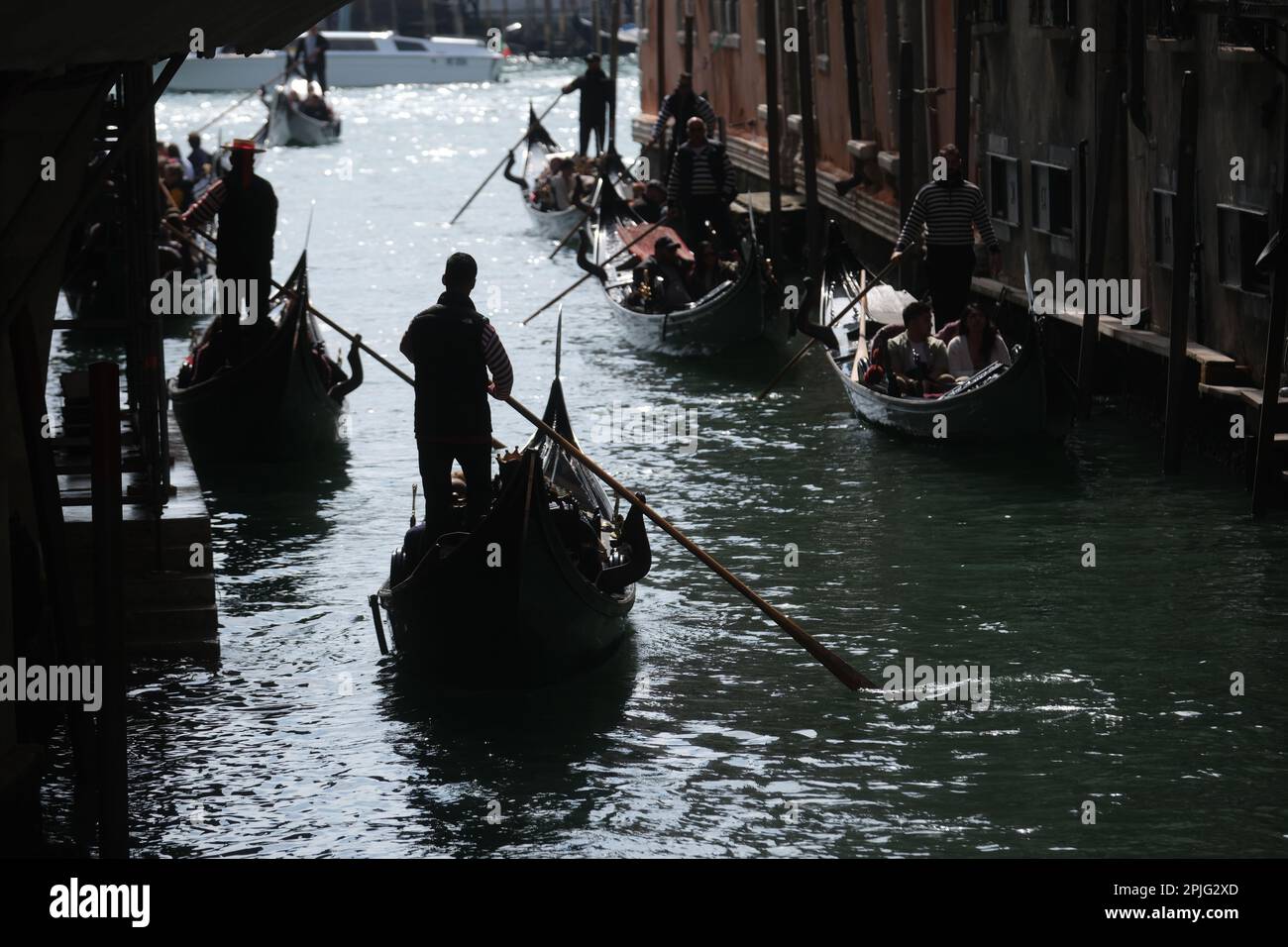 Gondoliere rudern ihre Gondeln mit Touristen an Bord entlang der Kanäle von Venedig, Italien, 2. April 2023 Stockfoto