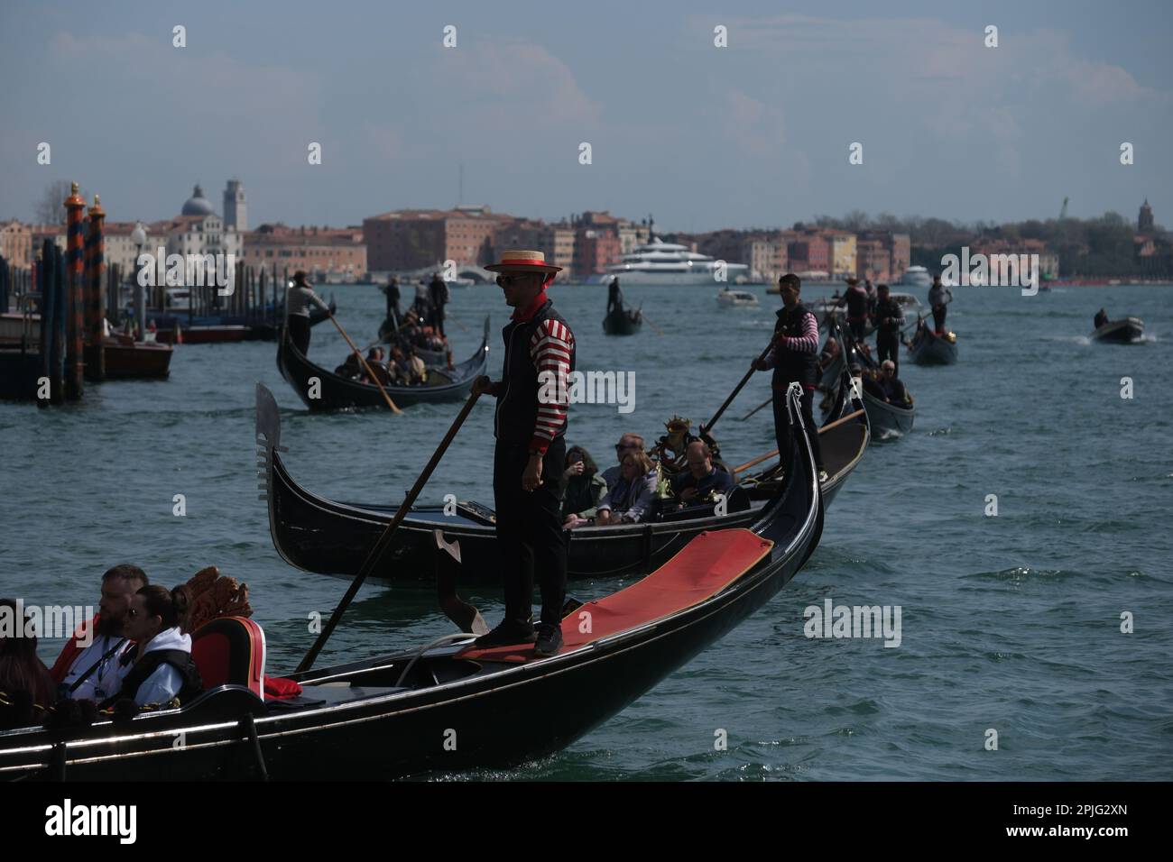 Gondoliere rudern ihre Gondeln mit Touristen an Bord entlang der Kanäle von Venedig, Italien, 2. April 2023 Stockfoto