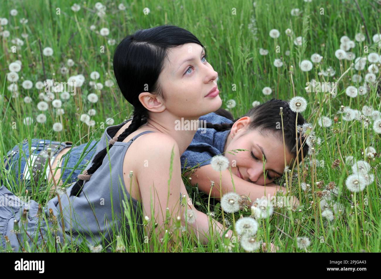 Zwei junge, schöne Frauen in stiller Kommunikation auf der Frühlingswiese Stockfoto