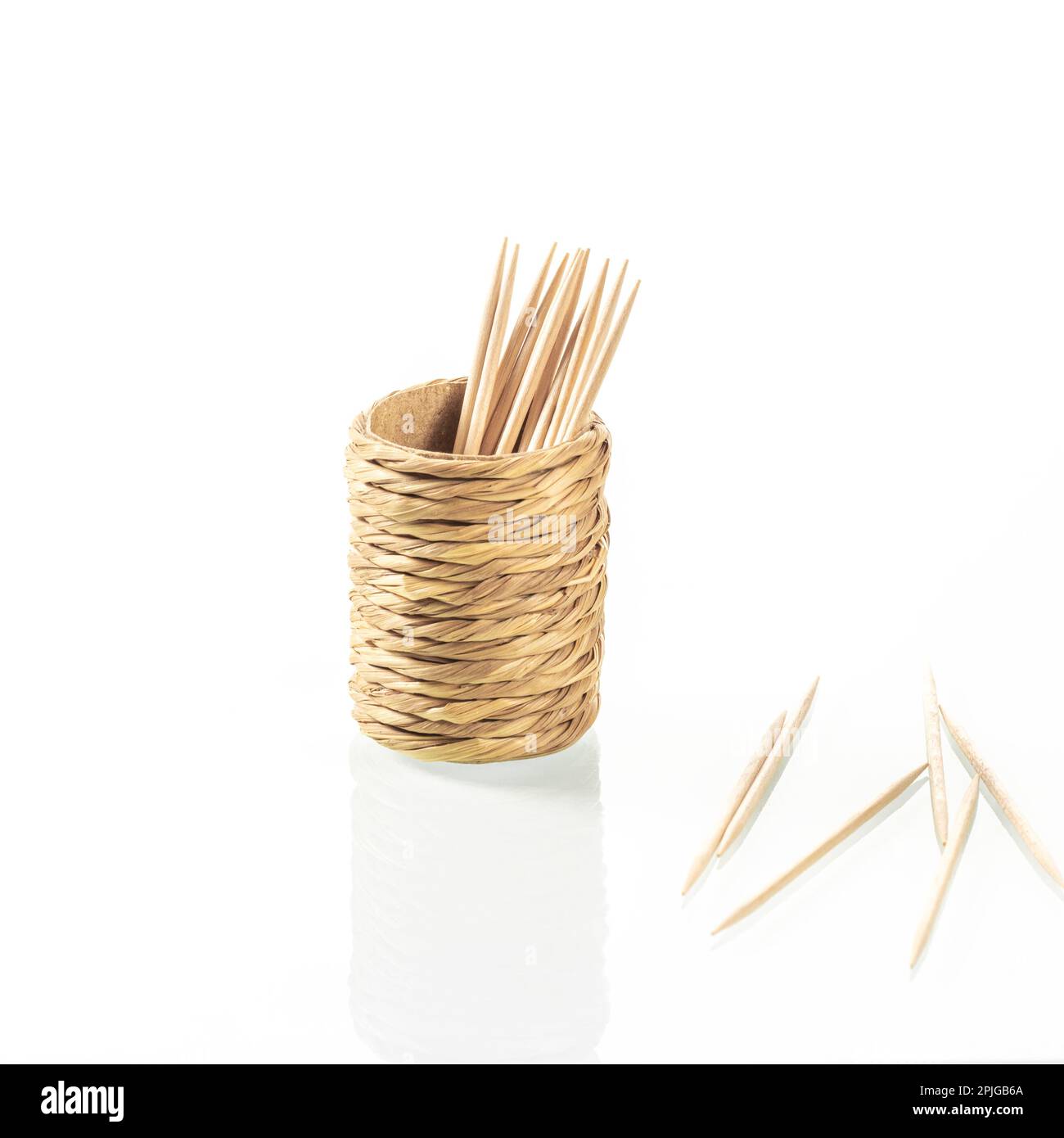 Becher aus Stroh für Zahnstocher mit Reflexion auf weißem Spiegelhintergrund für Nahaufnahmen Stockfoto