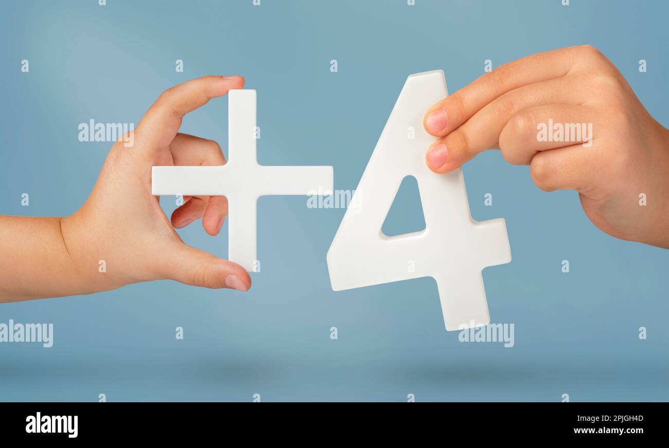 Die Zahl vier und das Pluszeichen in den Händen eines Kindes auf blauem Hintergrund. Weiße Nummer 4 plus Nahaufnahme. Fügen Sie drei Konzepte hinzu. Stockfoto