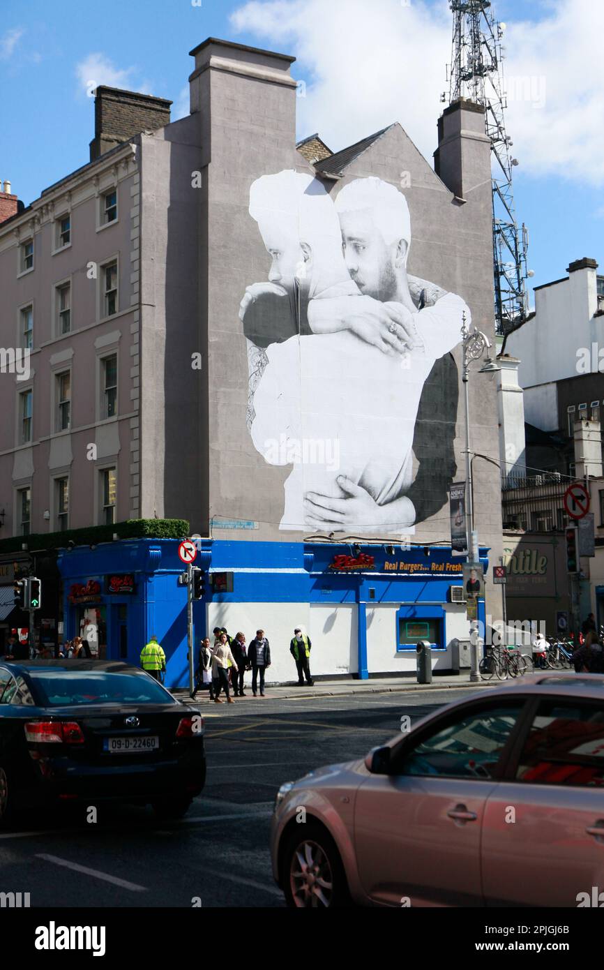 Zwei schwule Männer umarmen ein vierstöckiges Wandgemälde in der Innenstadt von Dublin, Irland, während der erfolgreichen Kampagne zur Legalisierung der schwulen Ehe auf der Emerald Isle. Stockfoto