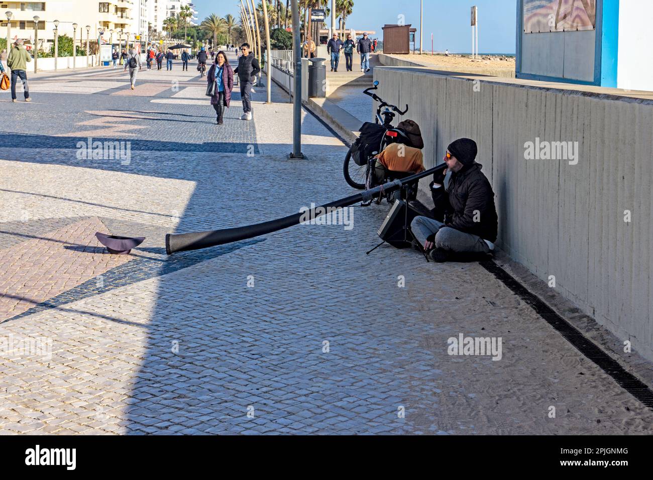 Ein Straßenkünstler, der auf der Promenade in Quarteira, Portugal, das Didgeridoo spielt. Stockfoto