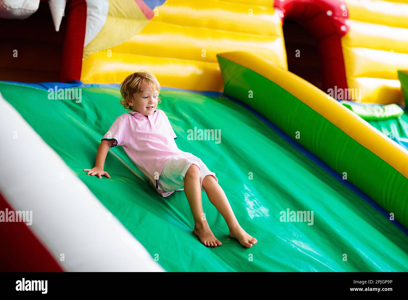 Kinder springen auf buntem Spielplatz-Trampolin. Kinder springen in aufblasbare Sprungburg auf Kindergarten Geburtstagsparty Aktivität und Spielzentrum Stockfoto