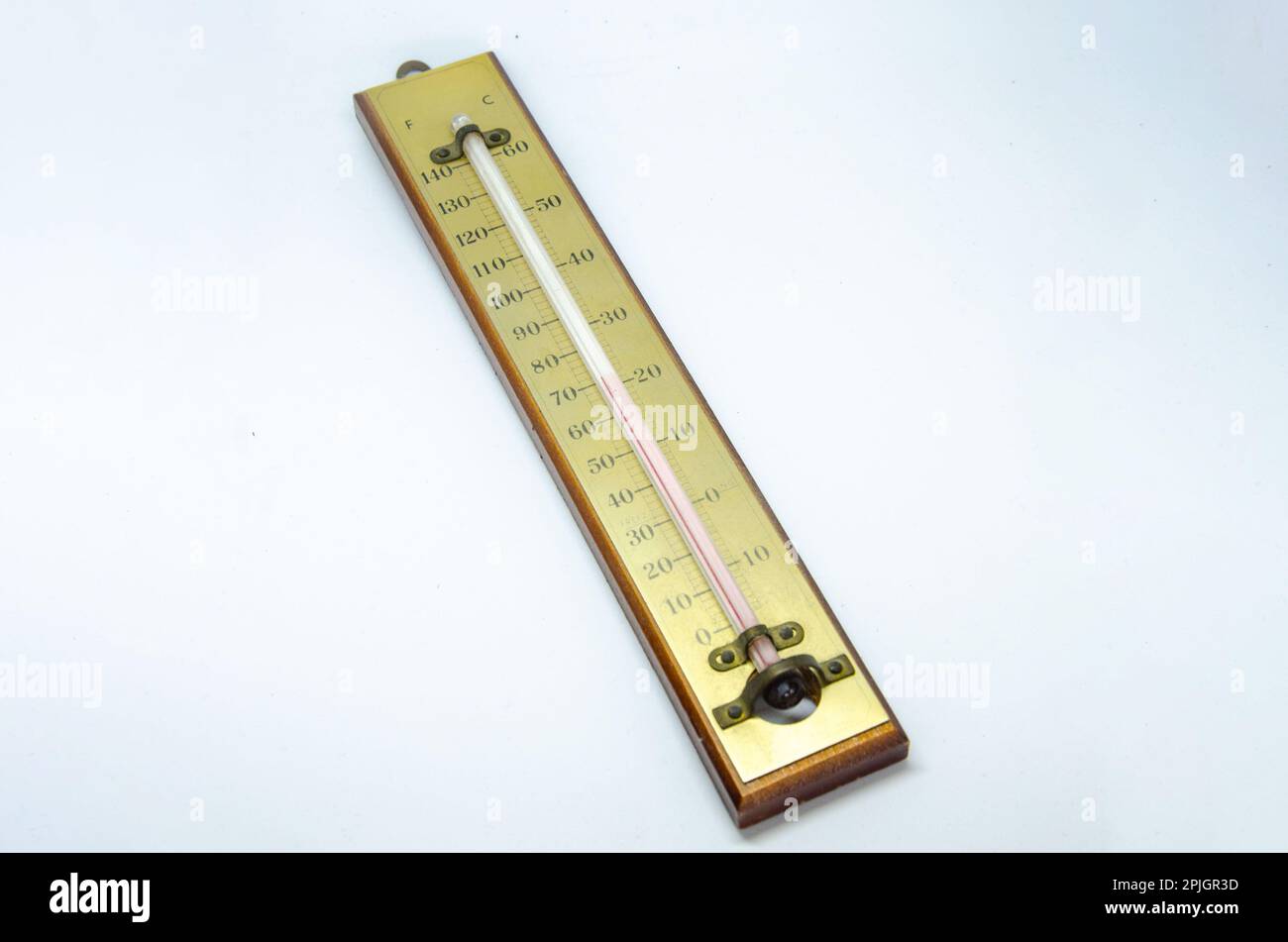 Ein altes Thermometer, das eine Flüssigkeit auf Basis von rotem Spiritus enthält, die zur Temperaturmessung eine Skala nach oben geht. Stockfoto