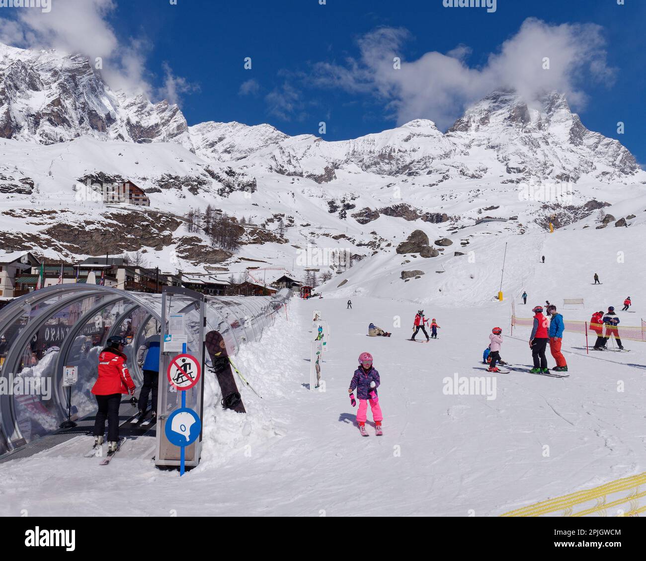 Skifahrer in der Säuglingsstation im Breuil-Cervinia, Aosta Valley Italien, mit einem mehrstufigen Skilift und dem schneebedeckten Cervino Berg, auch bekannt als Matterhorn, dahinter. Stockfoto